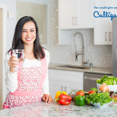 Young Hispanic Women Preparing a Meal Holding A Glass Of Water